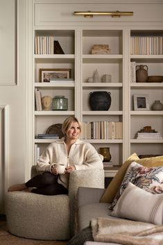 a woman sitting on a chair in front of a bookshelf with shelves behind her