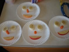 four paper plates with faces made to look like banana slices and carrots on them