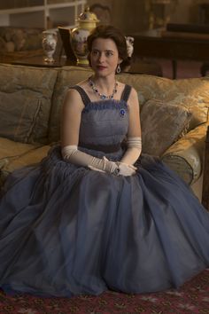 a woman sitting on top of a couch in a blue dress