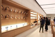 people are looking at headphones on display in a store with wooden shelves and shelving