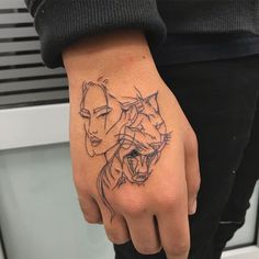 a woman's hand with a tattoo on it that has two cats in the middle