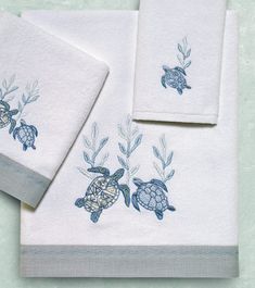 three towels with sea turtles on them, one is blue and the other is white