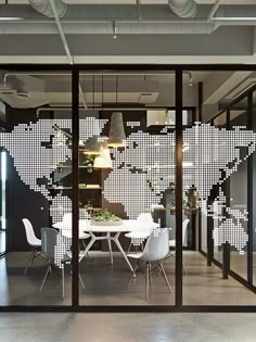 an office with a world map on the wall and white chairs in front of it