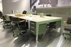 an office desk with chairs and a large poster behind it in a room that is empty