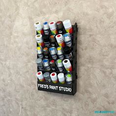 there is a rack with many cans of paint on the wall next to each other