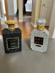 two black and gold perfume bottles sitting on top of a table