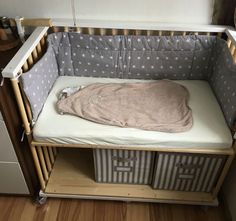 a baby crib with a blanket on top of it and two drawers underneath the crib