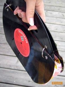 a person is holding an old record in their hand while standing on a wooden deck