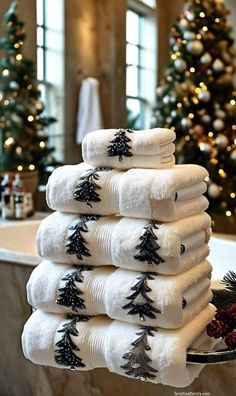 a stack of white towels sitting on top of a counter next to a christmas tree