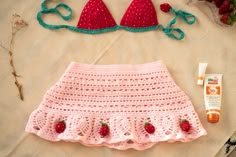 a crocheted skirt, strawberries and other items are laid out on a table