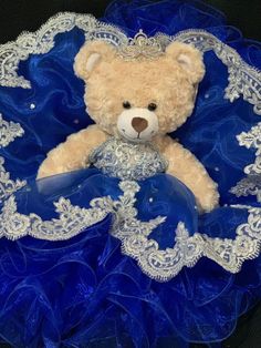 a teddy bear sitting on top of a blue and white doily with lace around it