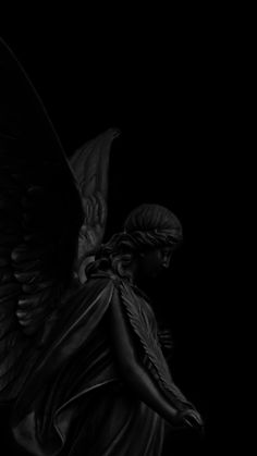 an angel statue in the dark with its wings spread out and it looks like he is holding