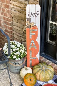 pumpkins and gourds are sitting on the front porch with a welcome sign