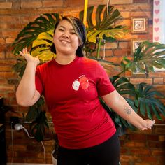 a woman standing in front of a brick wall with her arms out and hands up