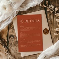 an orange and white brochure sitting on top of a wooden table next to flowers