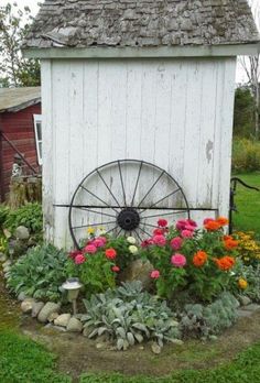 a garden with flowers and an old wheel