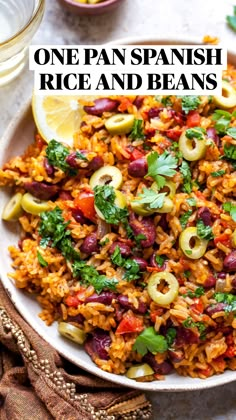 one pan spanish rice and beans on a plate with lemon wedges next to it