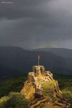 people are standing on the top of an old structure with a flag at the top