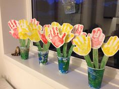 handprinted flowers in vases sitting on a window sill