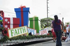 people walking down the street in front of a float with gifts and presents on it