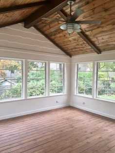 an empty room with wood flooring and ceiling fan in it's center window