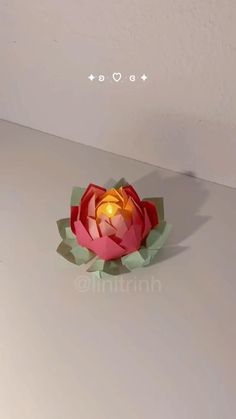 an origami lotus flower sitting on top of a white surface with the word love above it