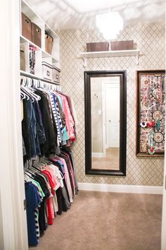 the closet is full of clothes and has a large mirror on the wall above it