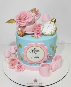 a blue cake with pink flowers and a clock on top