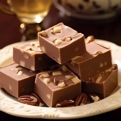 a white plate topped with pieces of chocolate covered in pecans and almonds next to a glass of wine