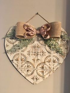 a heart shaped plaque with a bow hanging from it's side on a wall