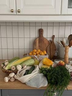 a kitchen counter topped with lots of fresh vegetables and fruits next to wooden cutting boards