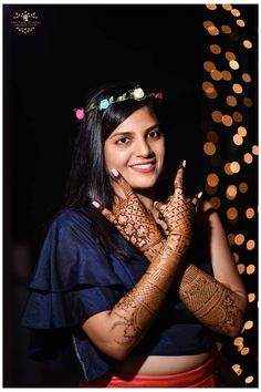 a woman with henna on her hands posing for a photo in front of some lights