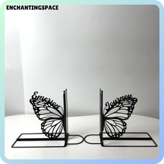 two metal butterfly bookends sitting on top of a white table next to each other