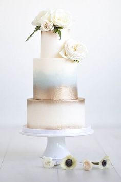 a white and gold wedding cake sitting on top of a table next to an iphone