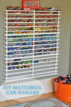 a white rack filled with lots of toy cars on top of a wall next to a window