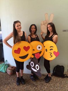 three girls are holding up paper plates with smiley faces on them and one has a hand print