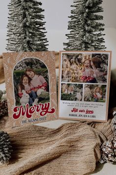 two christmas cards sitting on top of a table next to pine cones and fir trees