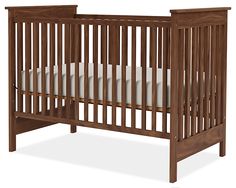 a wooden crib with white sheets on the bottom and sides, against a white background