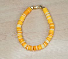 a yellow and white beaded necklace on a wooden table