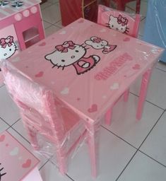 a table and chairs with hello kitty designs on the plastic covering over them in a room