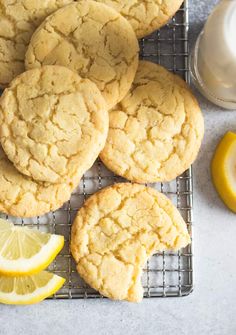 lemon cookies on a cooling rack next to a glass of milk and sliced lemons