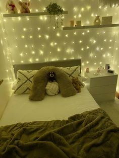 a teddy bear sitting on top of a bed in a room with lights around it