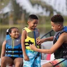 two boys and a girl in life vests on a boat