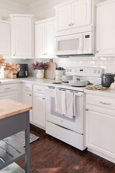 a kitchen with white cabinets and wood floors is pictured in this image, there are dishes on the stove