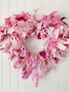 a pink wreath hanging on the side of a white door with ribbons attached to it