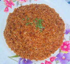 a white plate topped with brown rice covered in green leafy garnishes