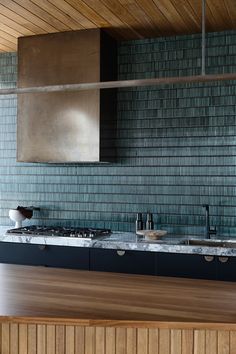 a kitchen with wooden floors and blue glass tile backsplashes on the wall