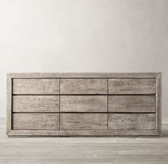 a wooden dresser sitting on top of a hard wood floor next to a white wall