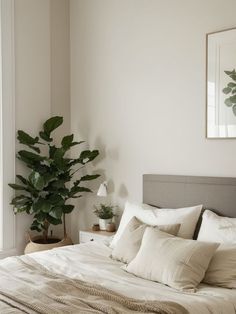 a bed with white sheets and pillows next to a potted plant in front of a window