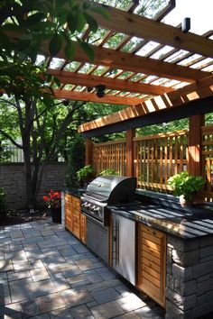 an outdoor kitchen with grill and sink under a wooden pergolan roof, surrounded by greenery